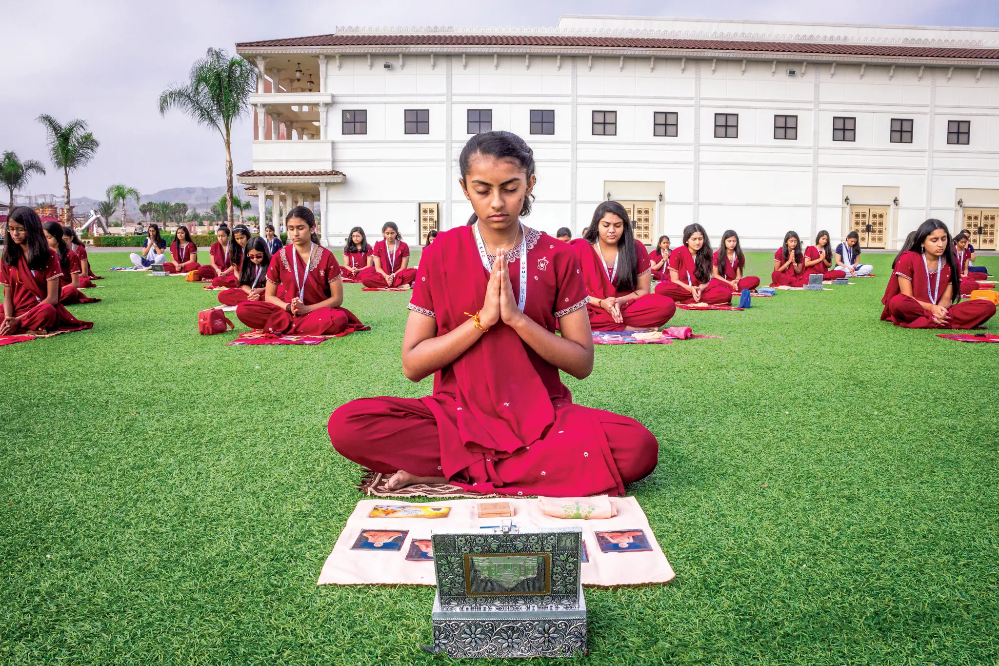 Young Hindu American boy with folded hands at a home puja altar with a lit diya