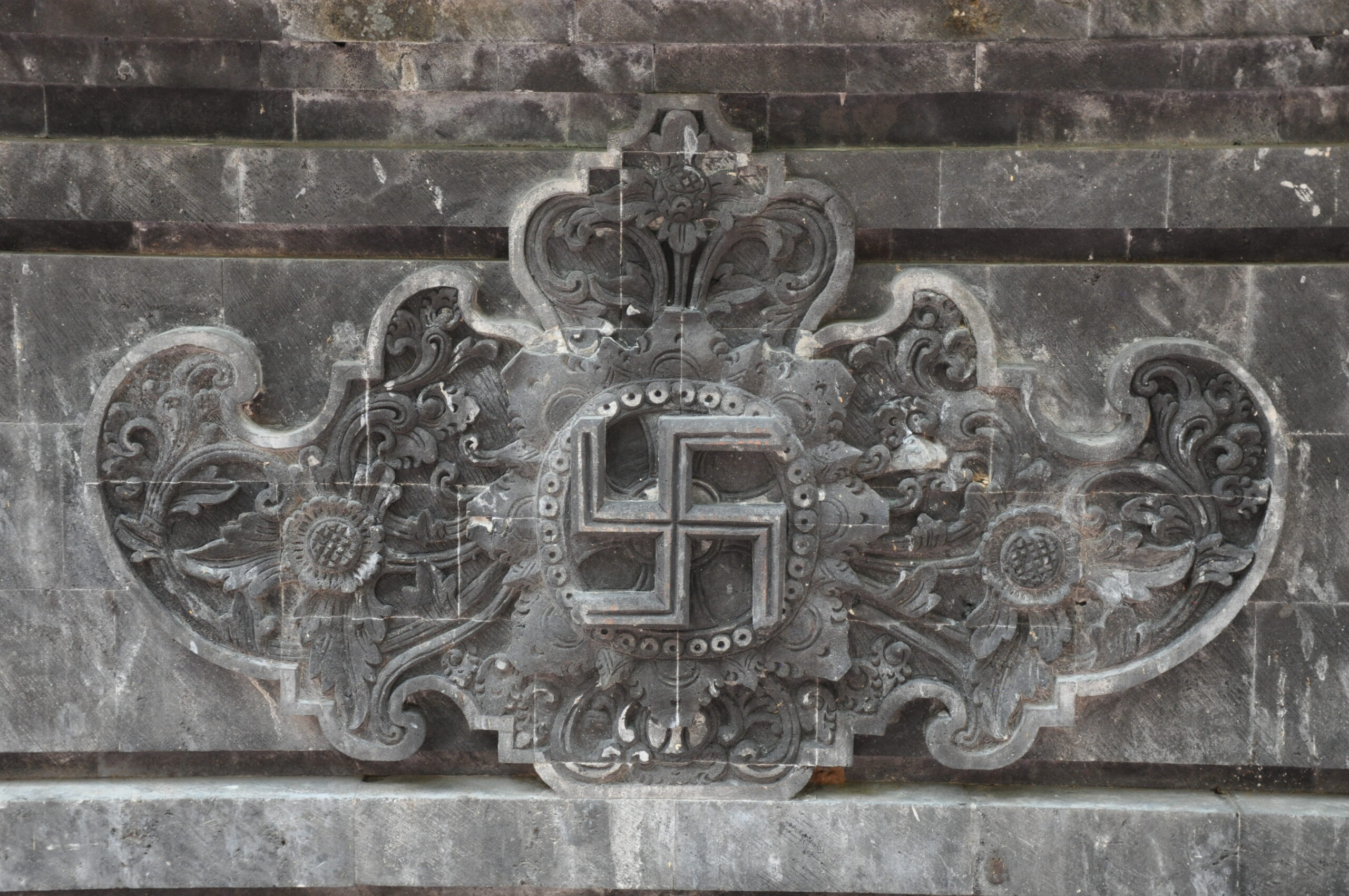 Ancient carved Swastika motif on a weathered stone temple wall